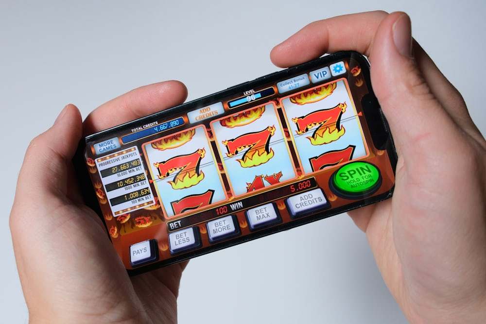 Tangan seseorang memainkan permainan slot pada ponsel pintar
